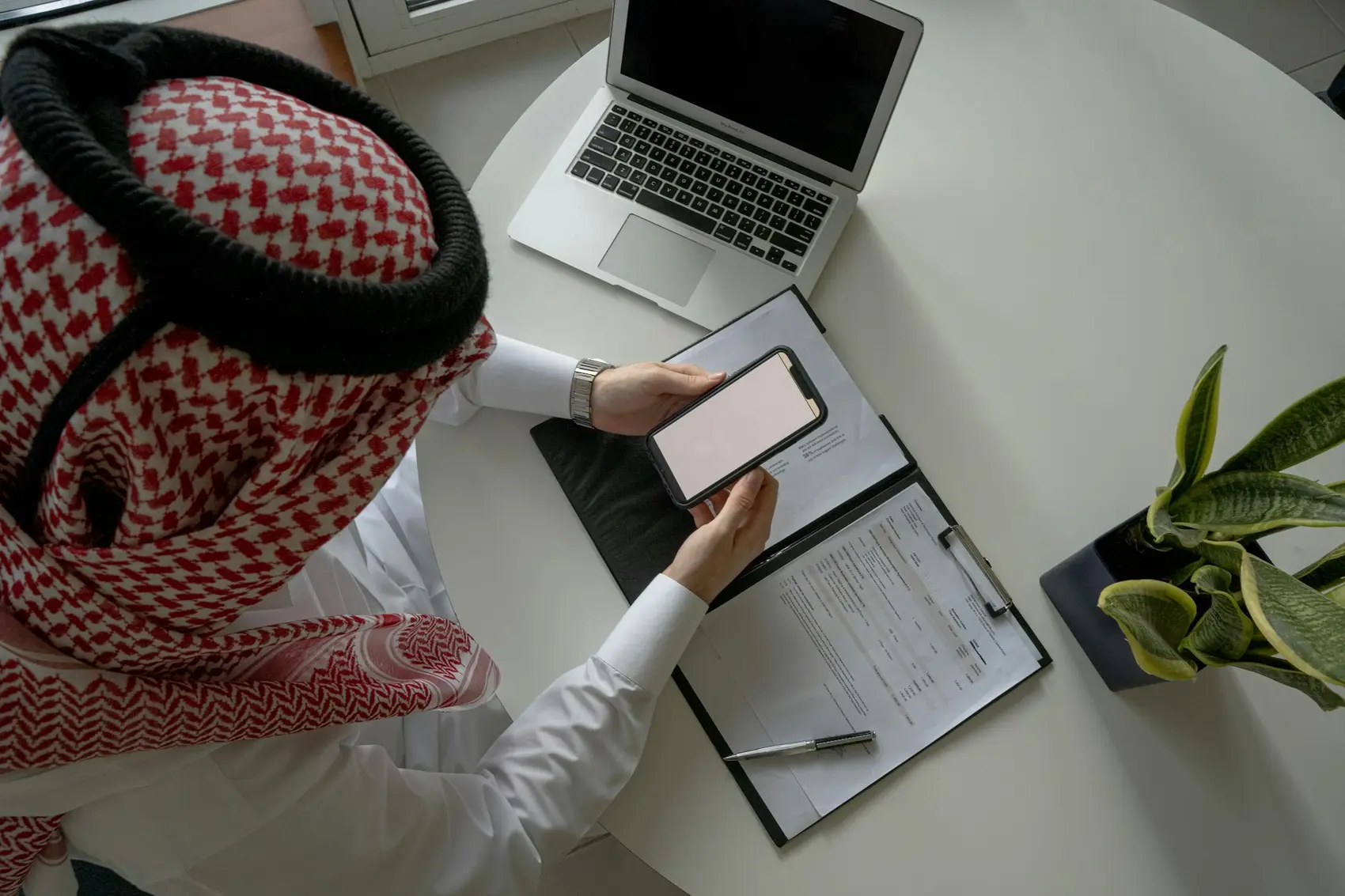 A Saudi businessman checking his phone at his desk
